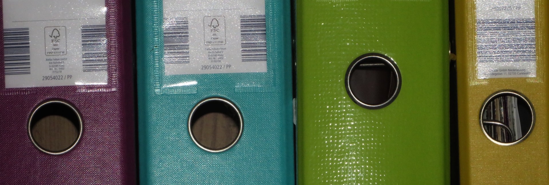 a row of colored binders on a shelf